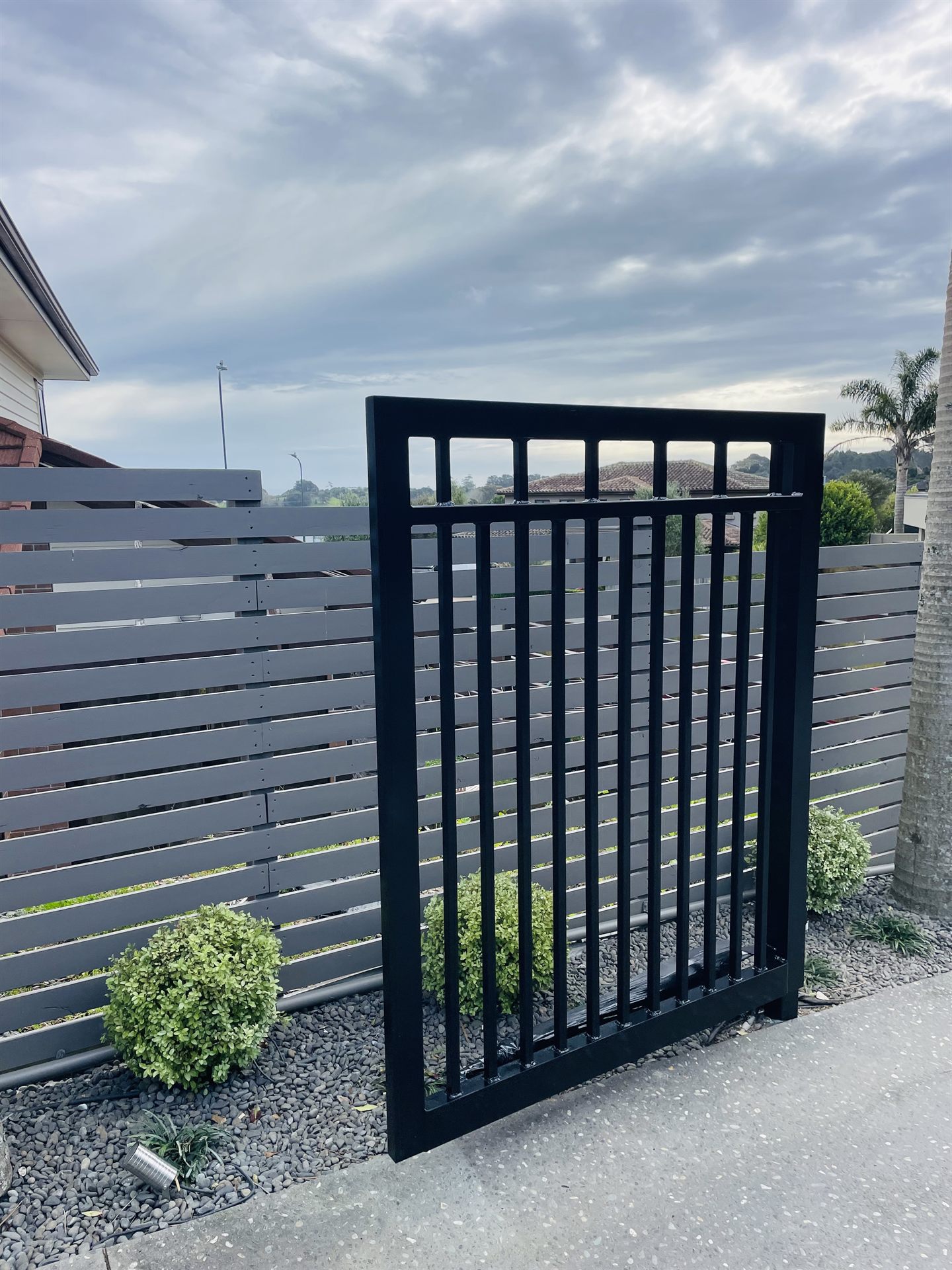 Painted black gate and grey timber slat fencing