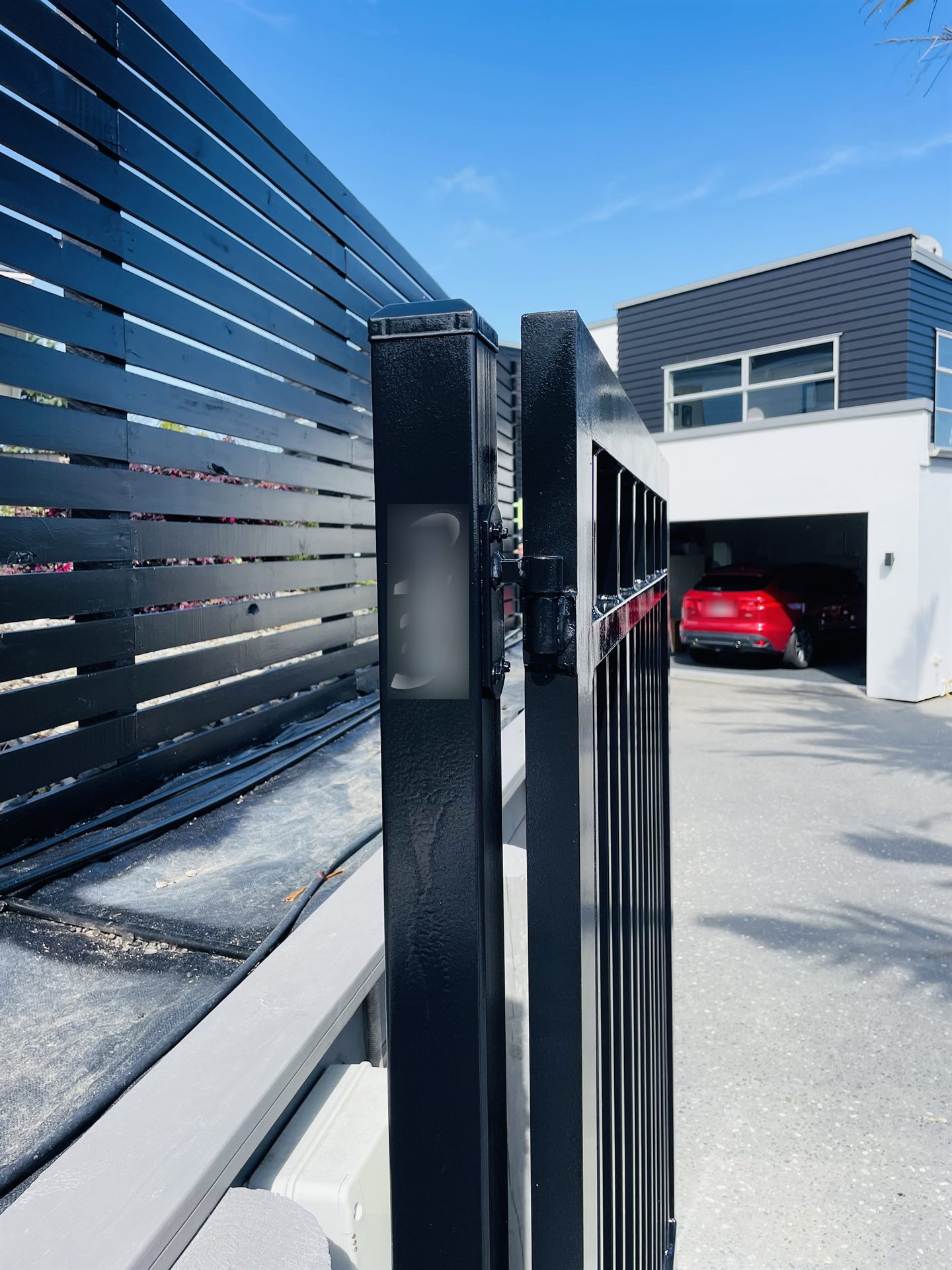 Close-up of a freshly painted black gate post and hinge