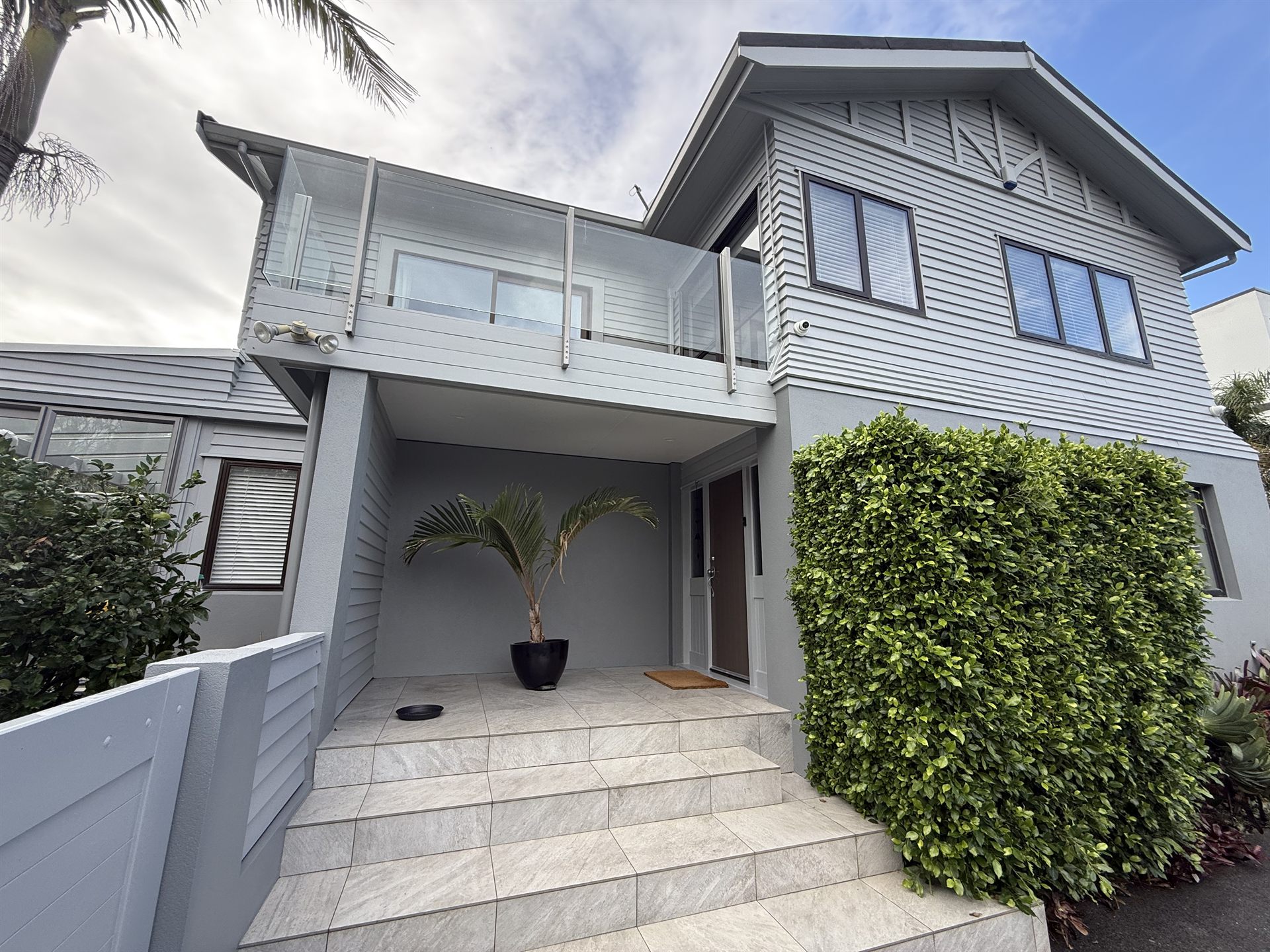 Repainted grey weatherboards and rendered walls at the front entry