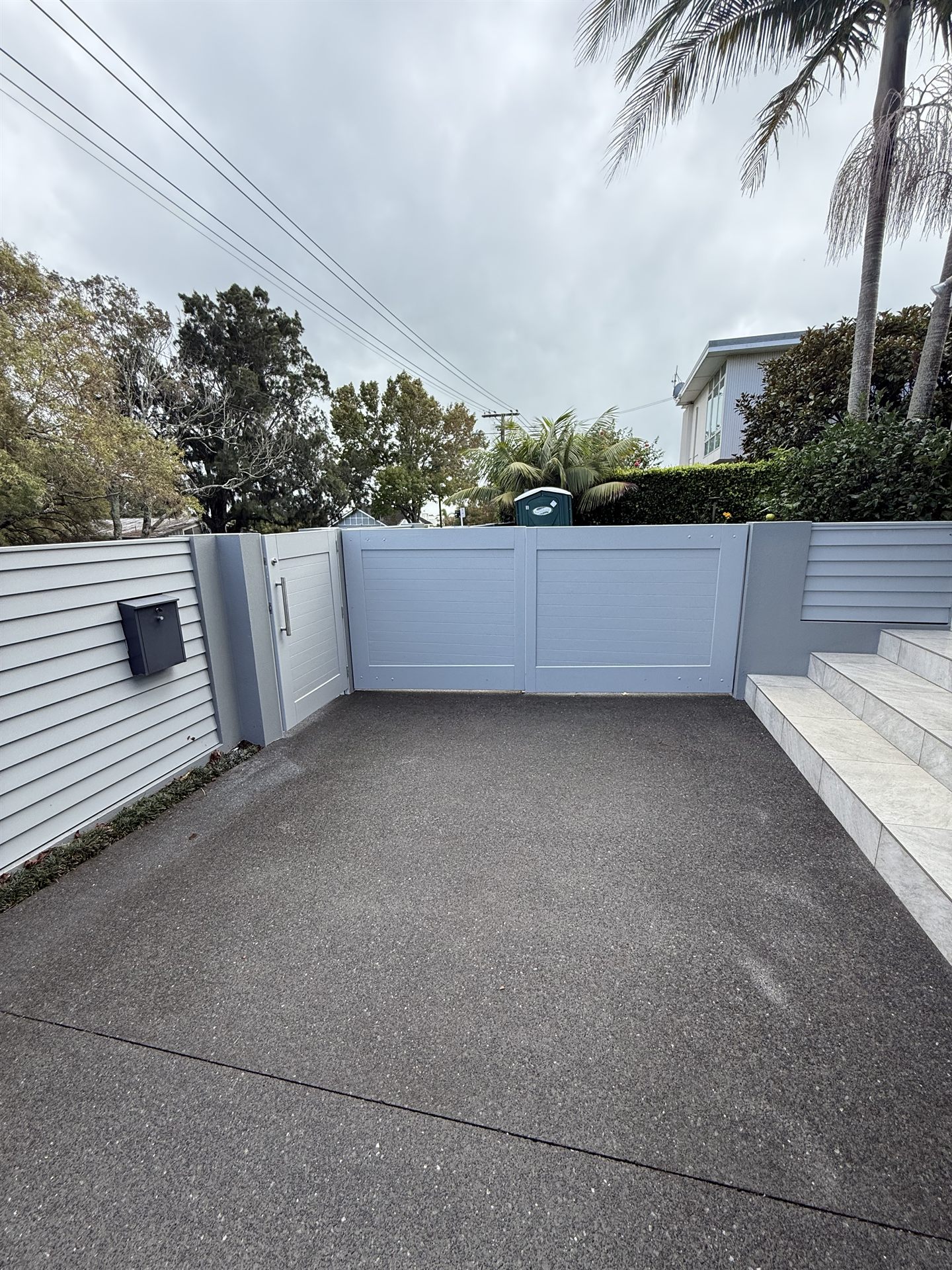 Repainted side gate and rendered wall along the driveway
