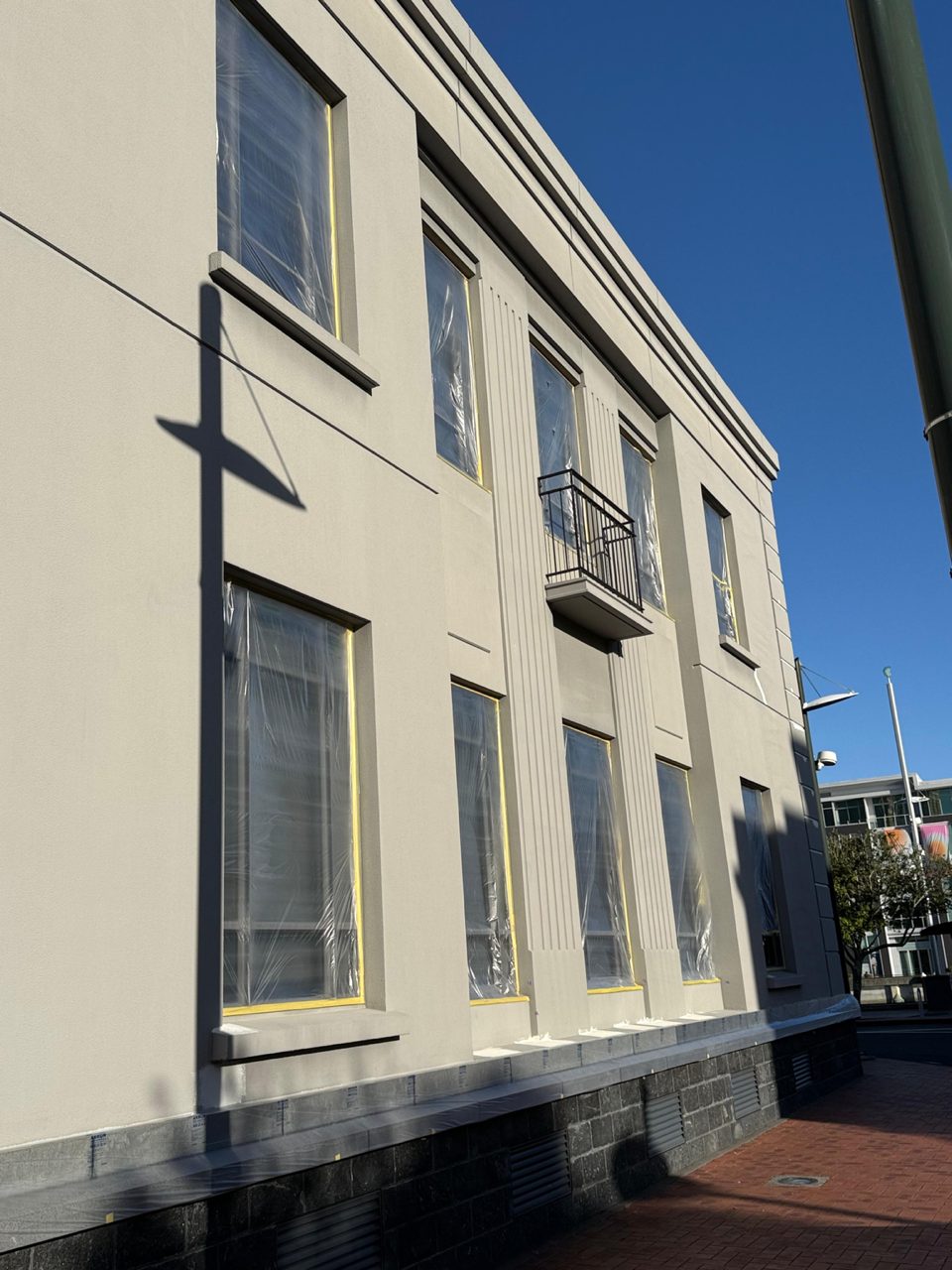 Masked and taped window joinery along the street elevation, prepped ahead of coating