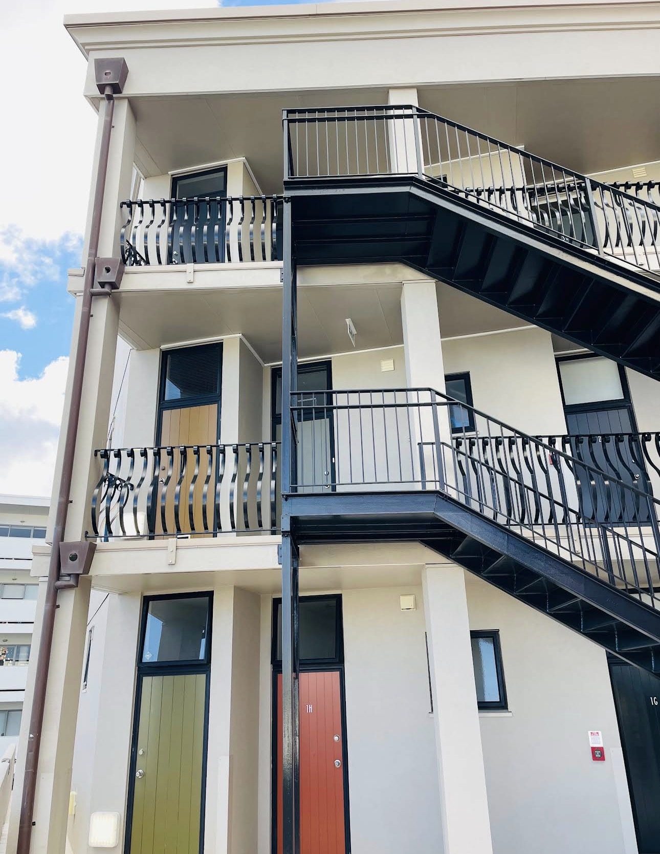 Repainted apartment corner with black steel access stairs and freshly finished entry doors