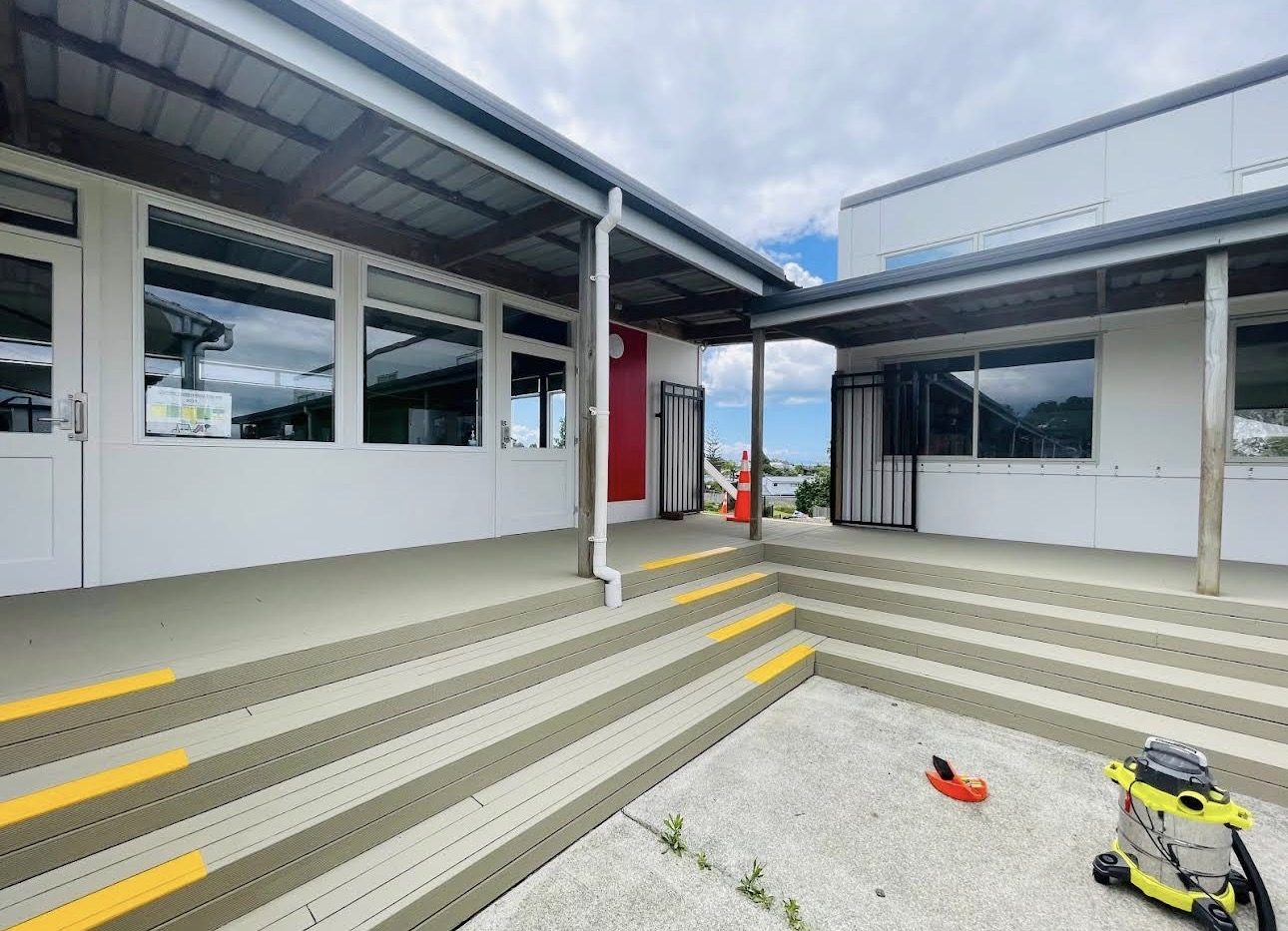 Recoated school courtyard deck with tiered steps and high-visibility yellow nosings on every stair edge