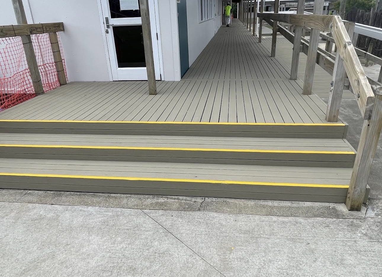 Freshly coated deck and steps with yellow nosings beside a school walkway